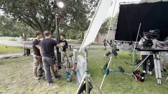 Film crew setting up lights and camera gear at a cemetery location