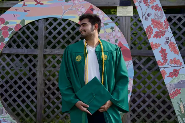 Graduation portrait — green gown with floral arch