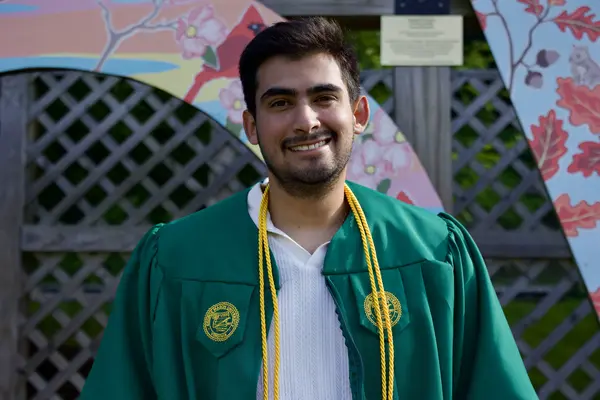 Graduation close-up — green gown with floral arch